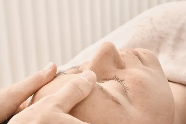 Le mani lavorano gli zigomi nel massaggio giapponese al viso