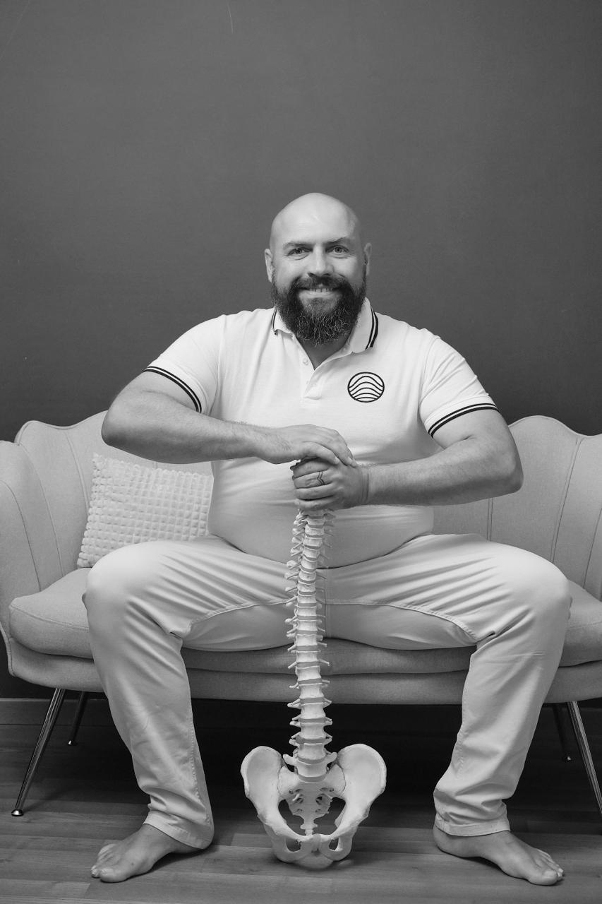 Cristian Bresadola seduto, con in mano un modello anatomico di colonna vertebrale